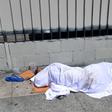 A homeless person' sleeping under a sheet on a sidewalk in Los Angeles, California on August 22, 2019, home to one of the nation's largest homeless populations