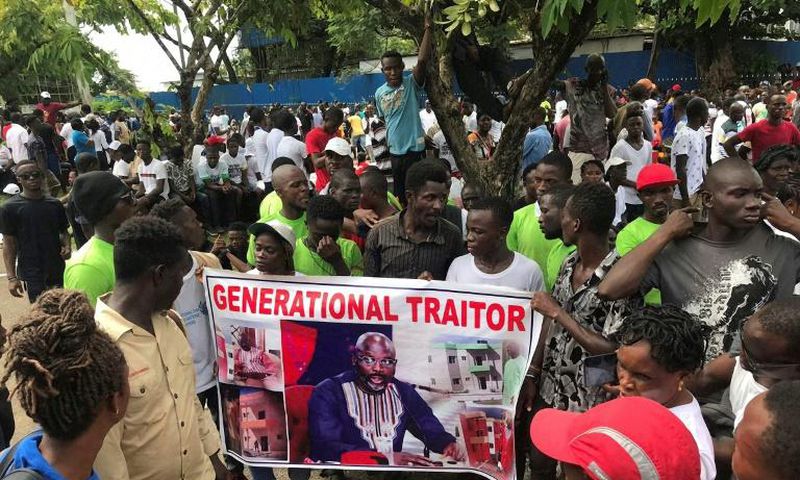 Demonstrators hold a poster portraying Liberian President George Weah as they gather outside the Liberian Mansion in Monrovia on June 7, 2019 during an anti-government march to protest inflation and corruption