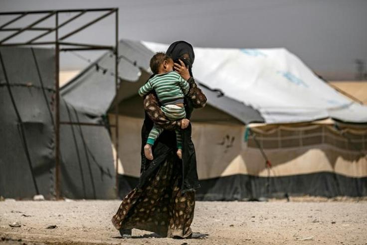 A woman carries a child in Al-Hol, one of three camps in Syria where 50 to 60 Belgian children of jihadists reside