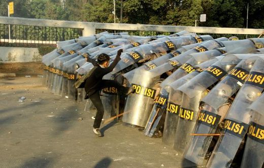 A protester attacks a police line during a demonstration in Jakarta