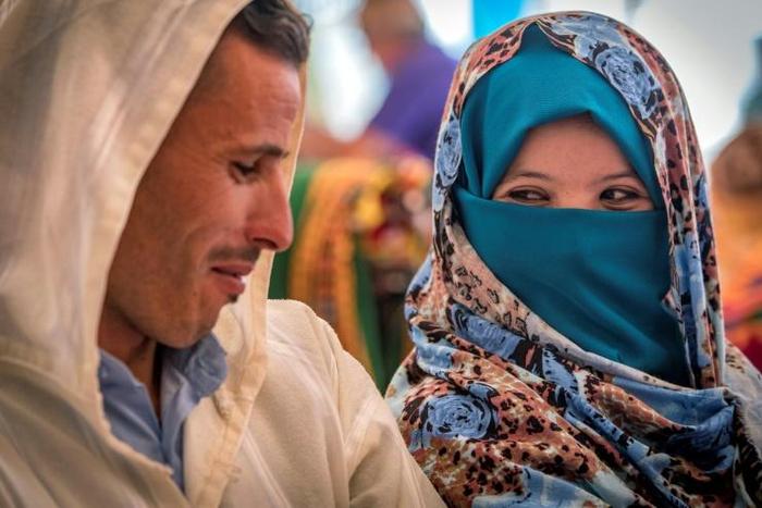 A young Amazigh couple smile at each other as they wait for their turn at a group wedding in Morocco's Atlas mountains