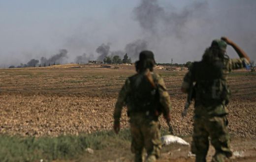 Turkish-backed Syrian fighters watch as smoke billows from the Syrian border town of Tal Abyad