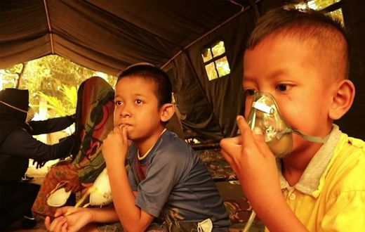 Indonesian children get a dose of oxygen from a Red Cross volunteer. UNICEF says the forest fires are puttling nearly 10 million children at risk from the toxic air