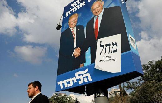 An Isreaeli man walks past an election billboard for the Likud party, showing US President Donald Trump (L) shaking hands with Prime Minister Benjamin Netanyahu in Jerusalem: Trump said Israel's latest election will be "50/50"