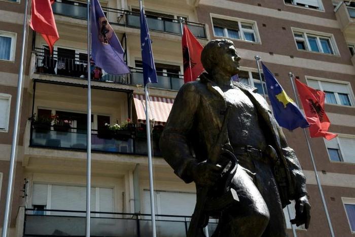 Kosovo and Albanian flags fly behind a statue of a former Kosovo Liberation Army commander in Pristina in 2014