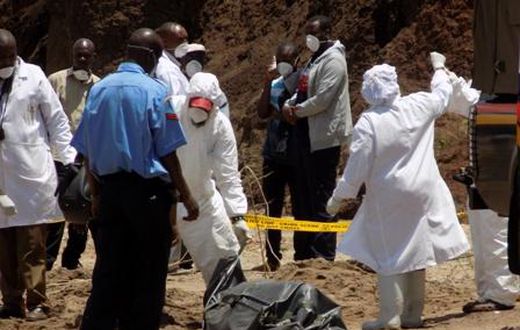 Detectives stabd next to the body of murdered Catholic priest Michael Kyengo