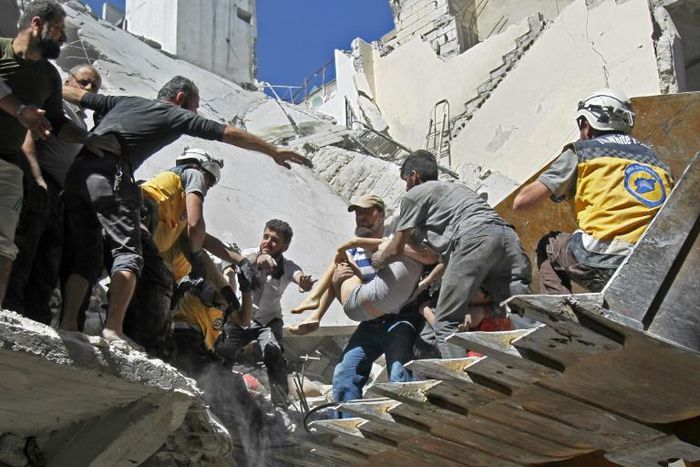 White Helmet rescuers and civilians extract a child from the rubble of a building destroyed during an air strike reportedly by Syrian regime forces and their allies on the town of Ariha, in Syria's Idlib province on May 27, 2019