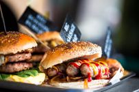 Close up of fresh flame grilled burgers with sausages displayed in a row at food market