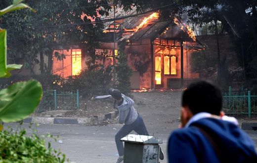 A building goes up in flames in Jakarta as a protester hurls rocks at police during violent demonstrations against the government's proposed change to the criminal code