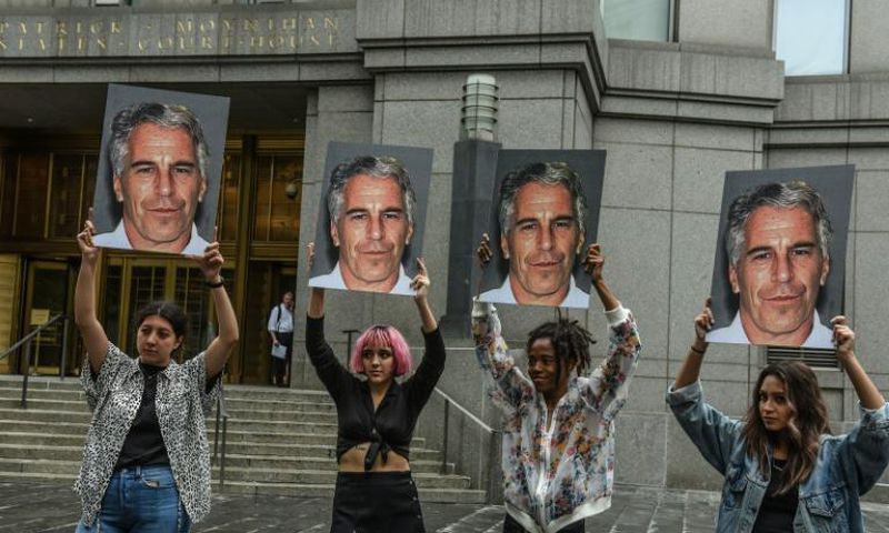 People hold signs of Jeffrey Epstein outside the federal courthouse in New York City on July 8, 2019, as Epstein was charged for sex trafficking minors