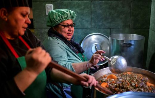 Women serve food at a soup kitchen which feeds at least 200 people hit hard by the economic crisis