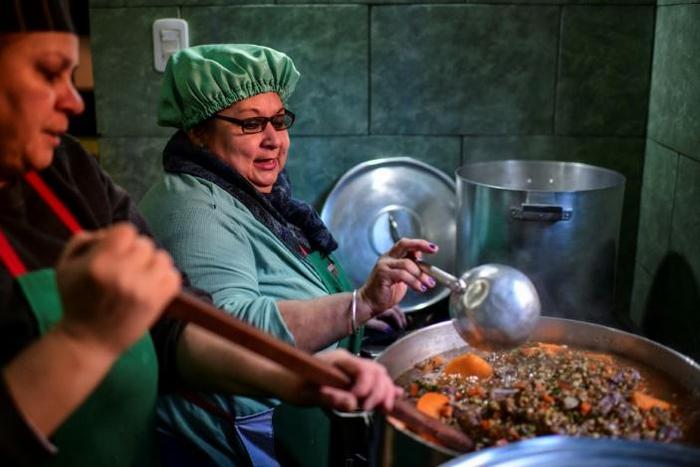 Women serve food at a soup kitchen which feeds at least 200 people hit hard by the economic crisis