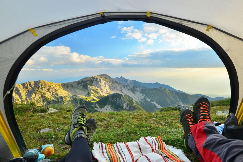 Tent view of mountain range with hiking boot in the foreground