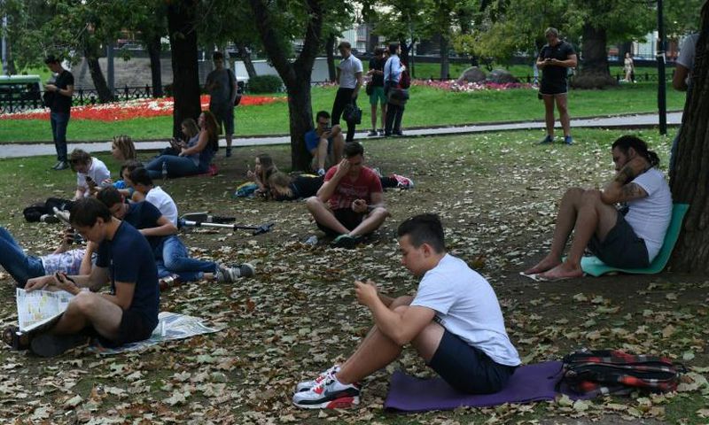 People look at their smartphones in central Moscow in August 2016 -- dating app Tinder has now been required to register with Russian security services