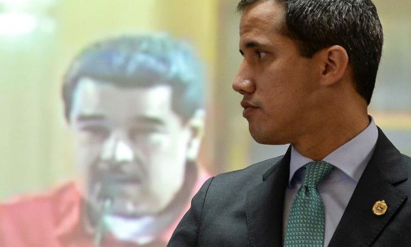 Venezuela's National Assembly leader and self-proclaimed acting president Juan Guaido gestures in front of a screen depicting Venezuelan President Nicolas Maduro during a session at the National Assembly in Caracas