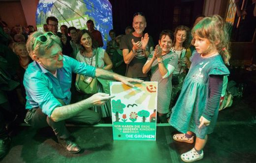 Austrian Green party head Werner Kogler holds a placard reading 'We only borrowed the earth from our children' after the exit poll results came in on Sunday