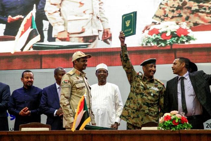 Sudan's protest leader Ahmad Rabie (R), flashes the victory gesture alongside General Abdel Fattah al-Burhan (2nd-R), the chief of the military council, after signing the "constitutional declaration" on Saturday
