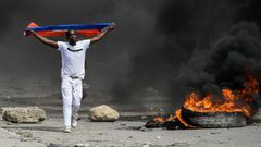 A demonstrator waves a Haitian flag during a protest against President Jovenel Moise on October 4, 2019 in Port-au-Prince