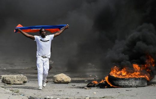 A demonstrator waves a Haitian flag during a protest against President Jovenel Moise on October 4, 2019 in Port-au-Prince