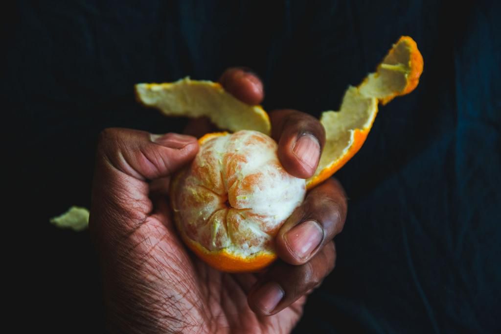 Cropped Hand Having Orange At Table