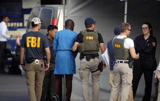 FBI agents holding one of the suspect arrested in the crack down on internet fraud