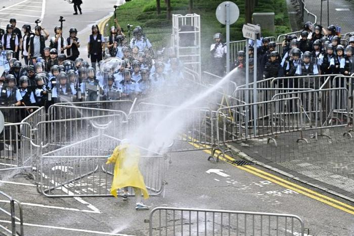 Police officers use a water canon on a lone protestor near the government headquarters in Hong Kong