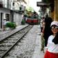 This photograph taken on June 8, 2019 shows a woman taking a selfie as a train passes in Hanoi's popular train street -- the selfie craze is universal