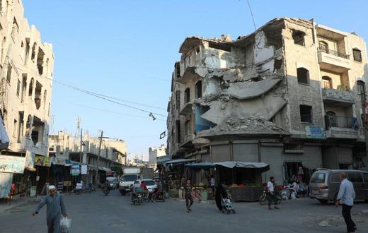 People walk near heavily damaged buildings in the rebel-held city of Idlib in northwestern Syria on September 16, 2019