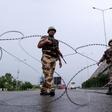 Security personnel stand guard at a roadblock on a near-deserted street in Jammu, Kashmir