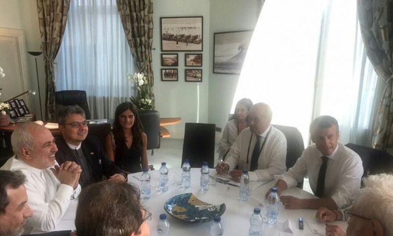 Mohammad Javad Zarif smiling broadly during talks with President Emmanuel Macron and other French officials