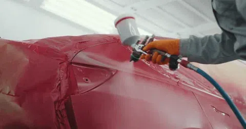 A car being spray-painted in a garage