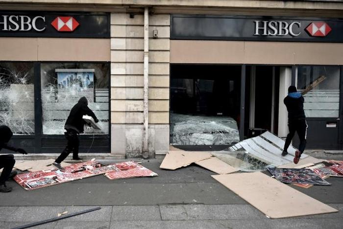 Demonstrators in Paris, some masked and hooded, broke shop windows along their route and threw projectiles at police in riot gear, who responded with tear gas