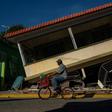 A man rides his bicycle past a collapsed house in Guanica, Puerto Rico on January 15, 2020, after a powerful earthquake hit the island