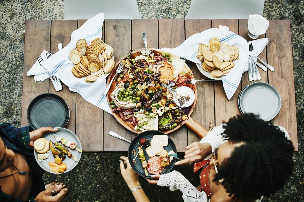 Overhead view of friends standing by table of appetizers during party