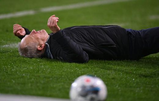 Freiburg head coach Christian Streich lies on the pitch after being barged by Frankfurt captain David Abraham on Sunday.