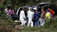 A team of forensic experts work in the site where seven bodies were found inside three abandoned vehicles