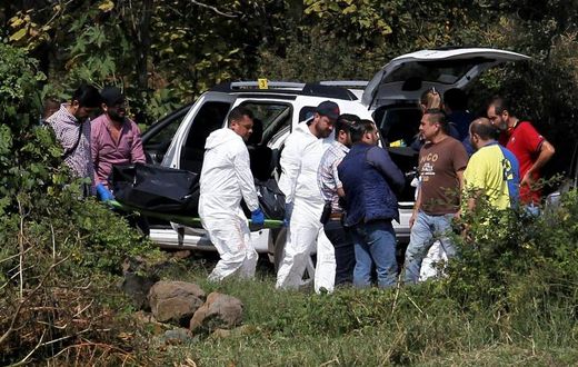 A team of forensic experts work in the site where seven bodies were found inside three abandoned vehicles