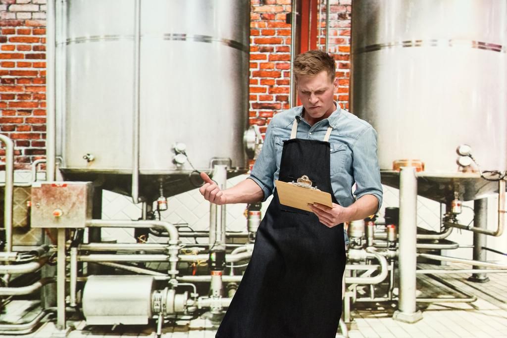 One person / one man only / waist up of 20-29 years old handsome people caucasian young men / male production line worker at the brewery / distillery / factory / food processing plant wearing button down shirt who is drunk / confusion / uncertainty