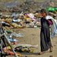 An Iraqi girl carrying a bag walks amidst piles of rubbish in a landfill in Diwaniyah, south of the capital Baghdad