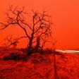 A long exposure picture shows a car commuting on a road as the sky turns red from smoke of the Snowy Valley bushfire on the outskirts of Cooma