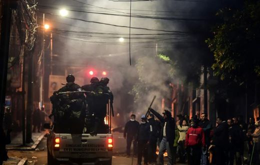 People gesture at policemen in La Paz, Bolivia on November 11, 2019 after president Evo Morales announced his resignation