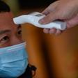 A hotel employee takes the temperature of a man who just arrived in the building in Wuhan
