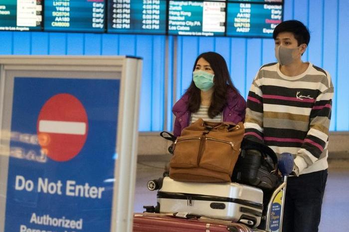Passengers wear masks to protect against the spread of the Coronavirus as they arrive at the Los Angeles International Airport