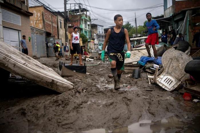 Children walk in the mud following heavy rains during the weekend, in Realengo neighborhood, in the suburbs of Rio de Janeiro, Brazil, on March 2, 2020