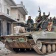 Syrian troops pass through a recaptured village in their final push on the strategic highway town of Maaret a-Numan, held by the rebels for seven years