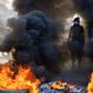 An Iraqi protester stands before burning tires at a roadblock in the central holy shrine city of Najaf