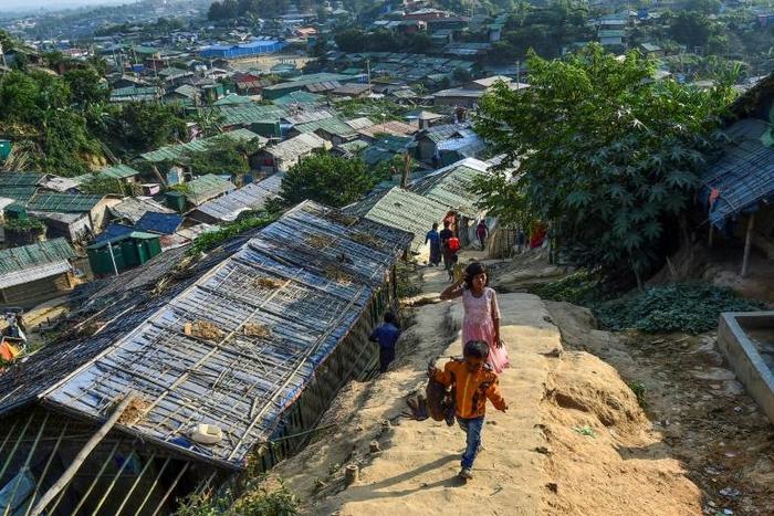 Rohingya refugees walk among makeshift houses in the Jamtoli Refugee Camp in Ukhia, Bangladesh in December 2019
