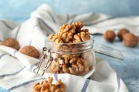 Glass jar with shelled walnuts on table