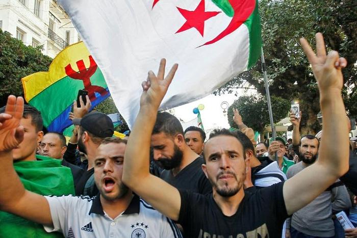 Algerian protesters, with the Berber flag in the background, chant slogans during anti-government demonstrations in the capital Algiers