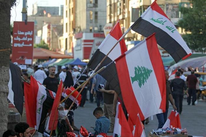 A Baghdad street vendor sells flags of Iraq and Lebanon, both gripped by anti-government protests